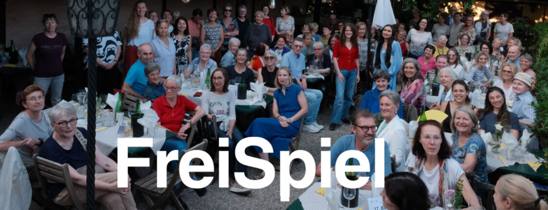 Freiwillige des Vereins FreiSpiel sitzen anlässlich des Sommerfestes in einem Hof und amüsieren sich