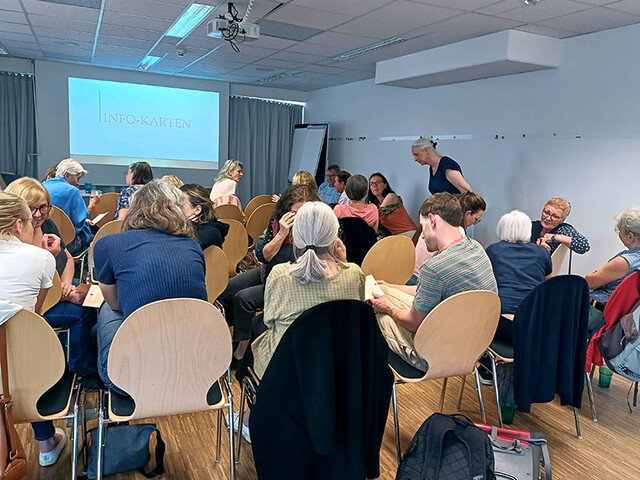 Gruppe von Ehrenamtlichen im Workshop tauscht sich in Kleingruppen über Infokarten aus